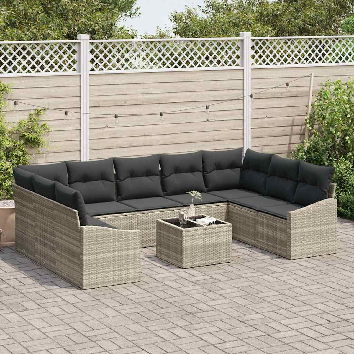 Ein Outdoor-Terrassenset mit grauen Kissen, einem kleinen Tisch und einem Holzzaun im Hintergrund. Das Set steht auf einer gepflasterten Terrasse.