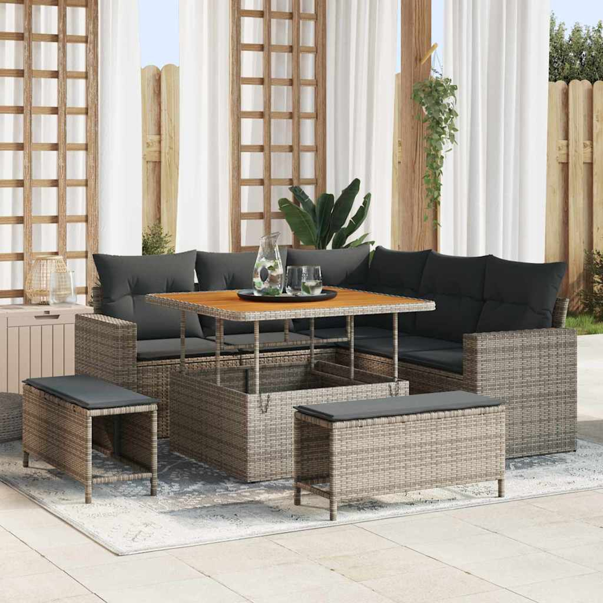 Garten-Terrassenset mit grauen Kissen, Holztisch und Bänken. Hintergrund: Vorhänge, Holzzaun und Pflanzen.