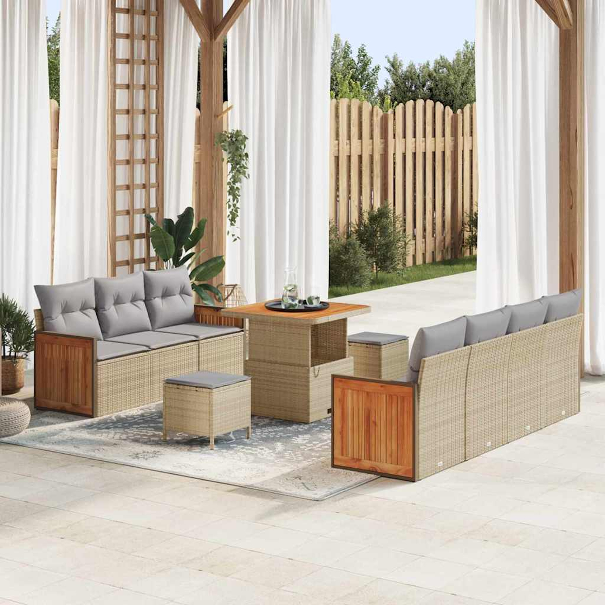 Set da patio esterno con divano, sedie, tavolo e pouf. Cuscini grigi, dettagli in legno e tende bianche. Sfondo: recinzione in legno e piante verdi.