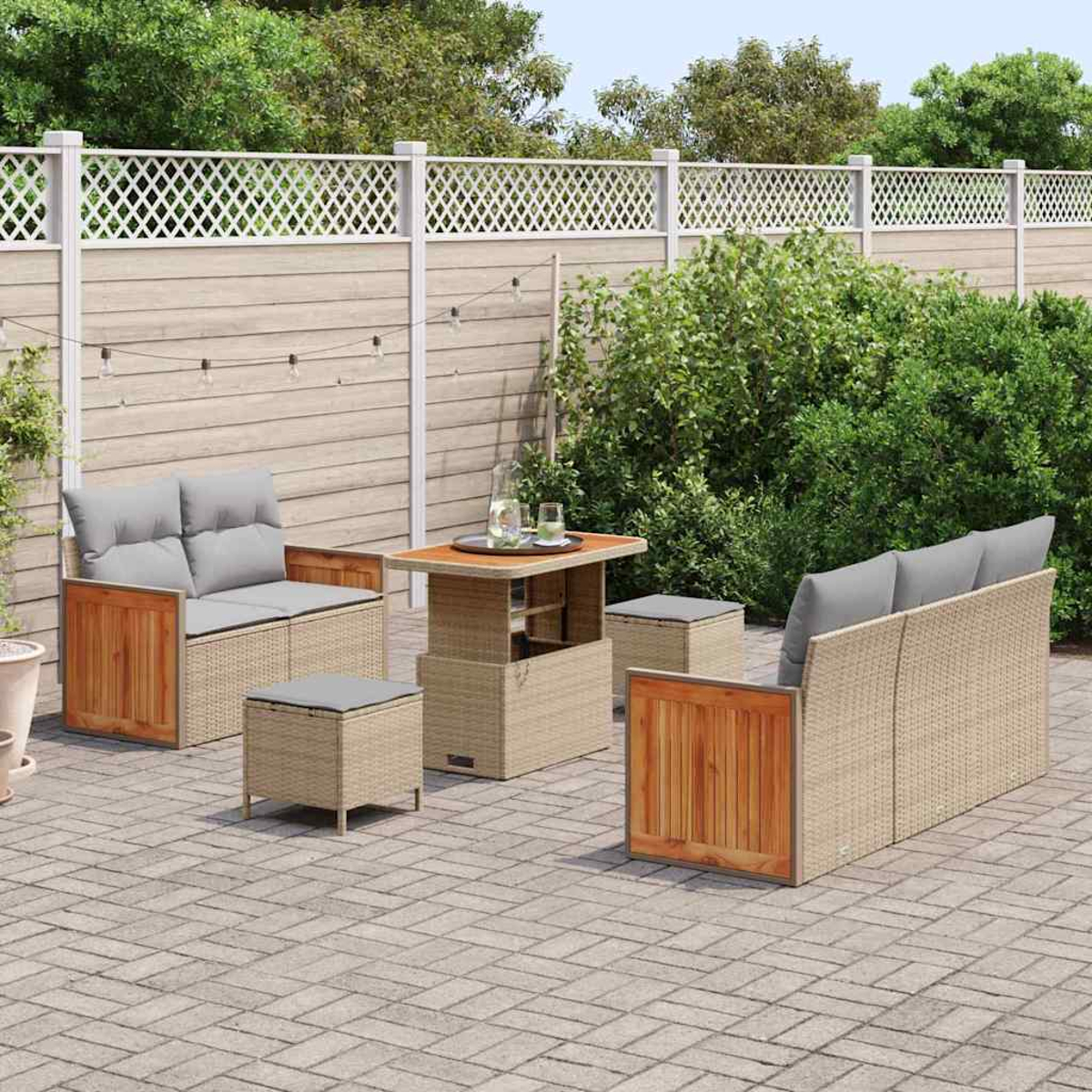 Set da patio: divano, due sedie, tavolo e pouf. Cuscini grigi, cornici intrecciate marrone chiaro con accenti in legno, su un patio in mattoni.