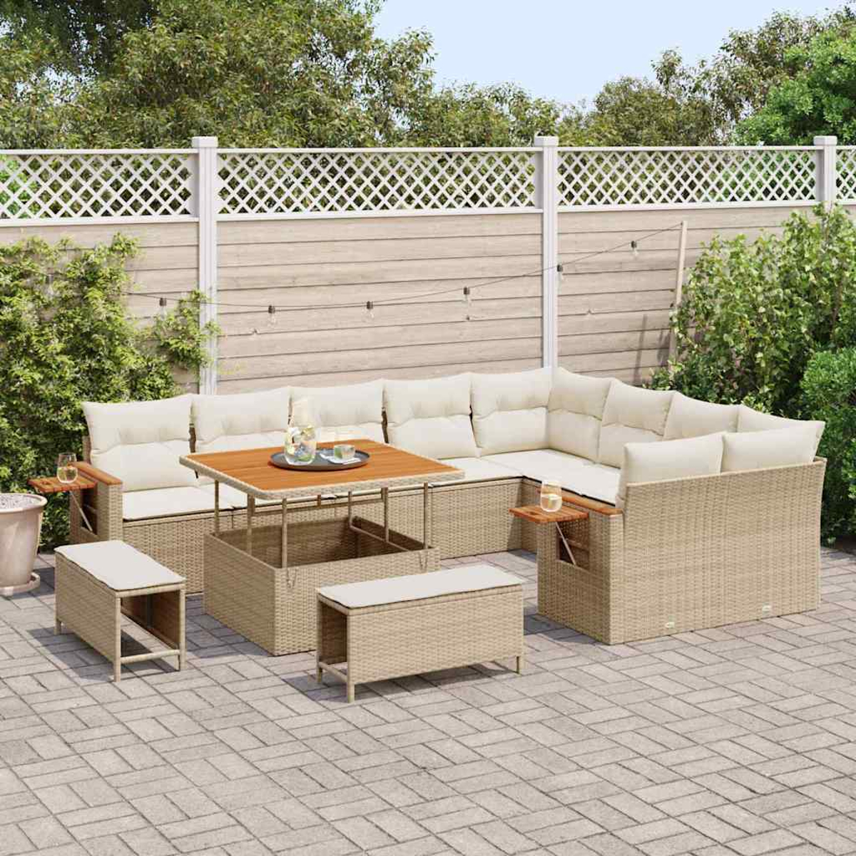 Outdoor-Rattan-Ecksofa-Set mit Kissen, einem Tisch und zwei Bänken, angeordnet auf einer Backstein-Terrasse. Im Hintergrund ein weißer Zaun und Grün.