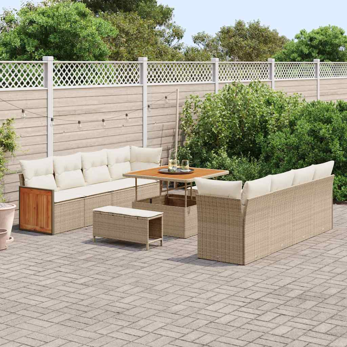 Garten-Terrassenset mit Sofa, Tisch und Bänken. Beige Korbmöbel mit cremefarbenen Kissen auf einer Ziegelterrasse, umgeben von Grün.