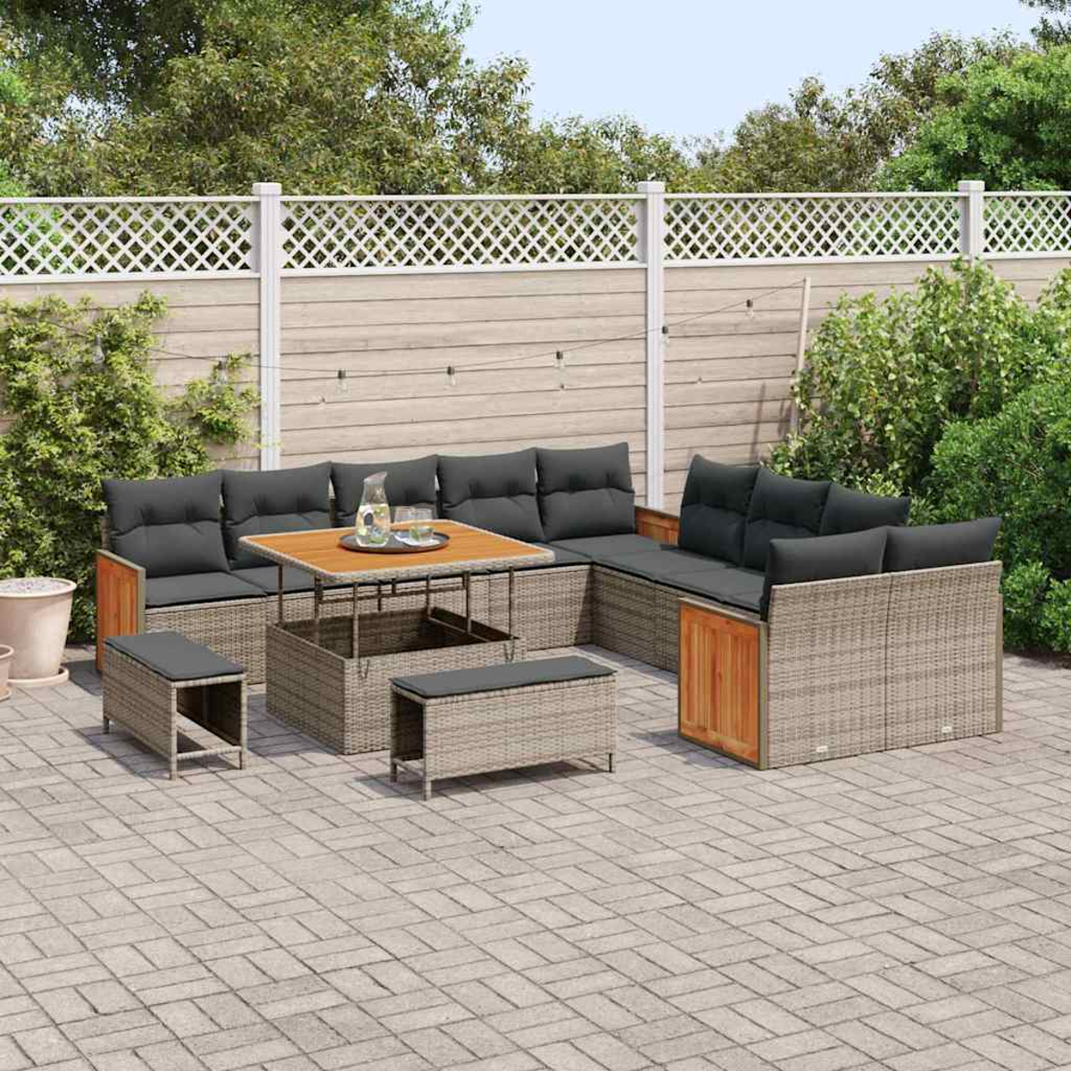 Set di mobili da patio: divano in vimini, panche e tavolo con cuscini grigi. Su un patio in pietra, con una recinzione bianca e verde.