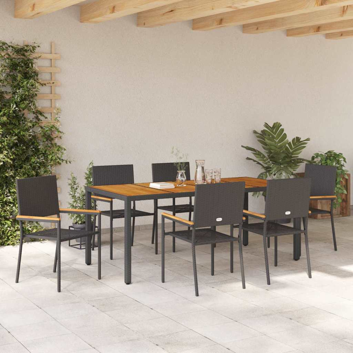 Essgruppe im Freien mit Holztisch und sechs schwarzen Stühlen. Grüne Pflanzen und eine neutrale Wand im Hintergrund.