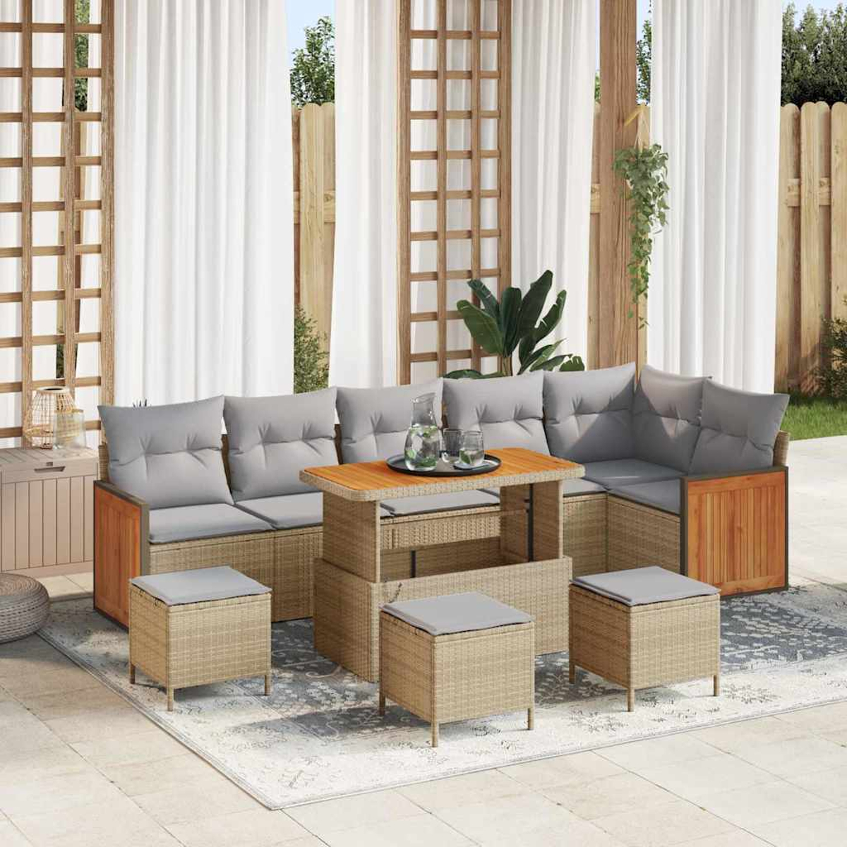 Gartenmöbel-Set aus Korbgeflecht. Enthält ein Ecksofa mit grauen Kissen, einen Couchtisch und passende Hocker auf einer Terrasse.