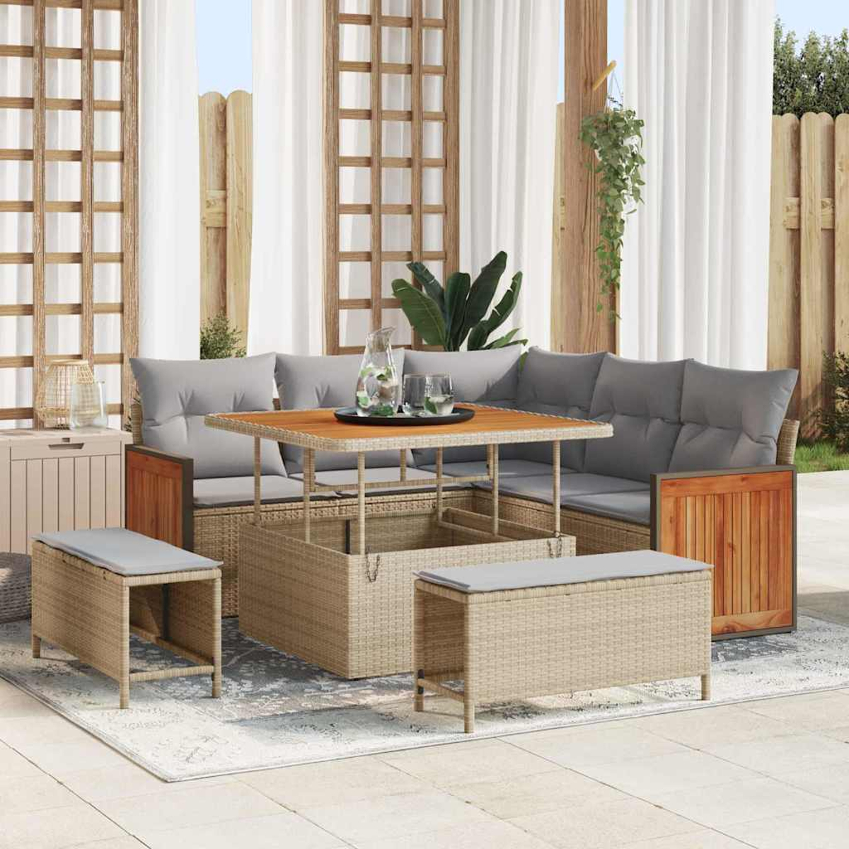 Gartenmöbel-Set aus Korbgeflecht mit grauen Kissen, einem Holztisch und zwei Bänken. Vorhänge und Pflanzen im Hintergrund.