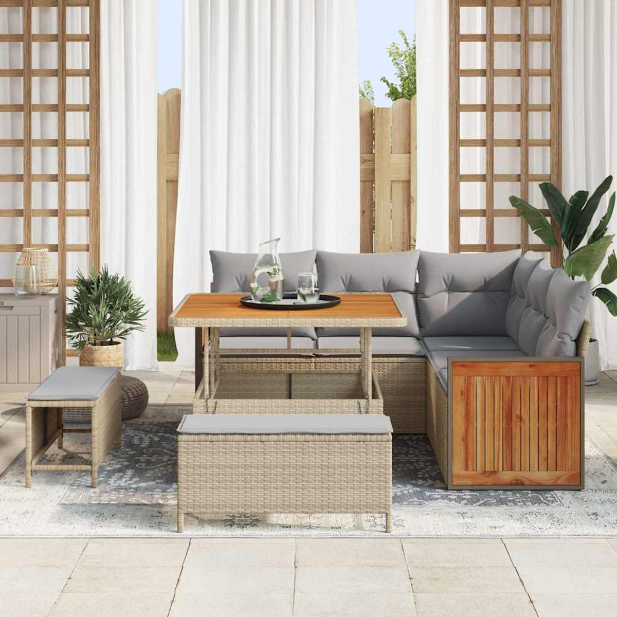 Outdoor-Sitzbereich mit Tisch, Sofa und Bänken. Weiße Vorhänge und ein Holzzaun sind im Hintergrund. Pflanzen und ein Teppich vervollständigen die Szene.