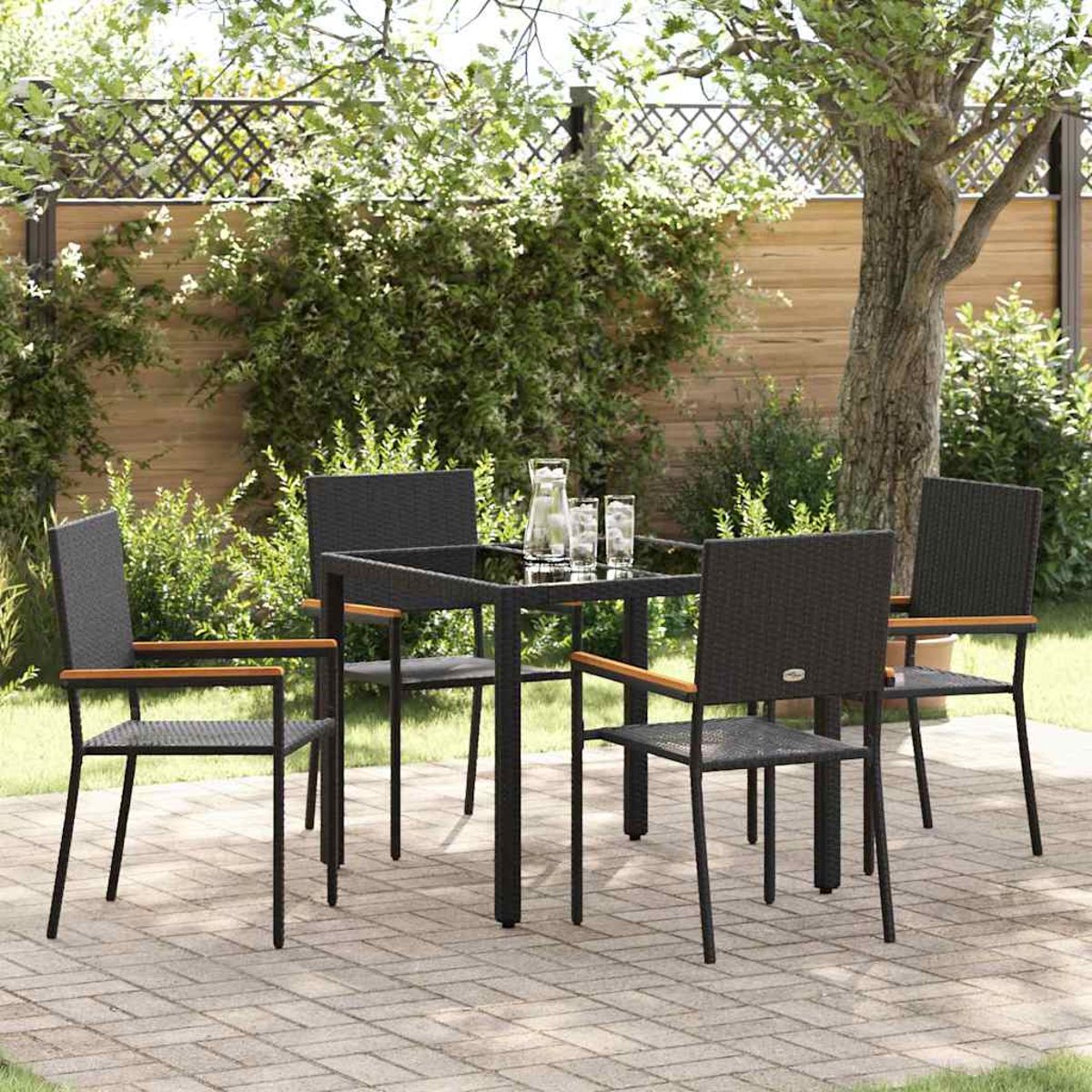 Ein Terrassenset mit einem schwarzen Tisch, vier Stühlen und einem Krug mit Gläsern auf dem Tisch in einem Garten.