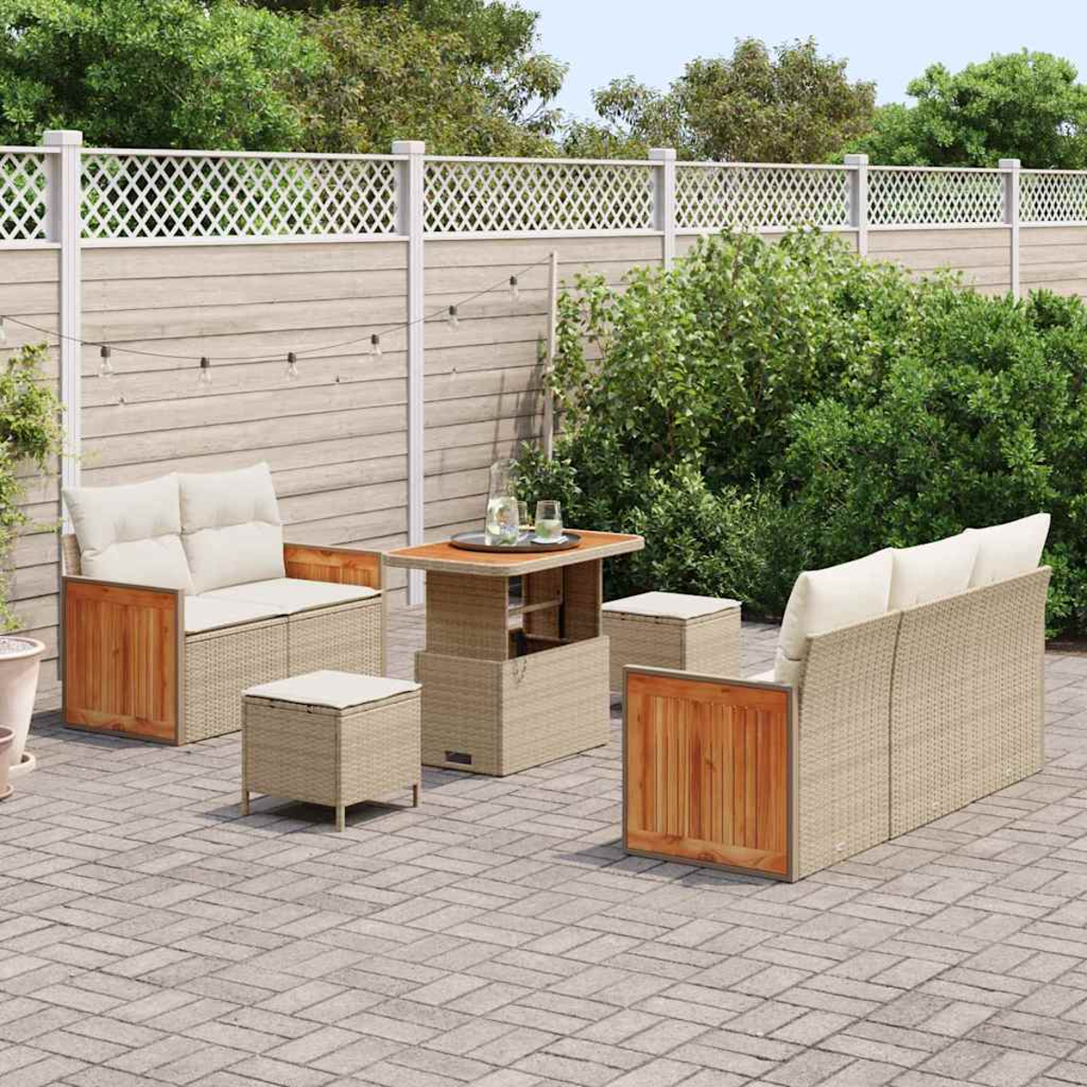 Set patio esterno con divano, sedie e tavolo. Cuscini beige e vimini. Accenti in legno. Patio in mattoni, recinzione bianca e fogliame verde.