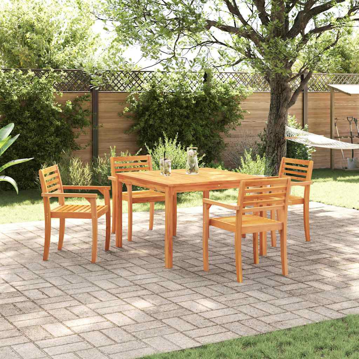 Ein hölzernes Terrassenset mit Tisch und vier Stühlen steht auf einer Ziegelterrasse. Im Hintergrund sind Holzzaun, Bäume und eine Hängematte zu sehen.
