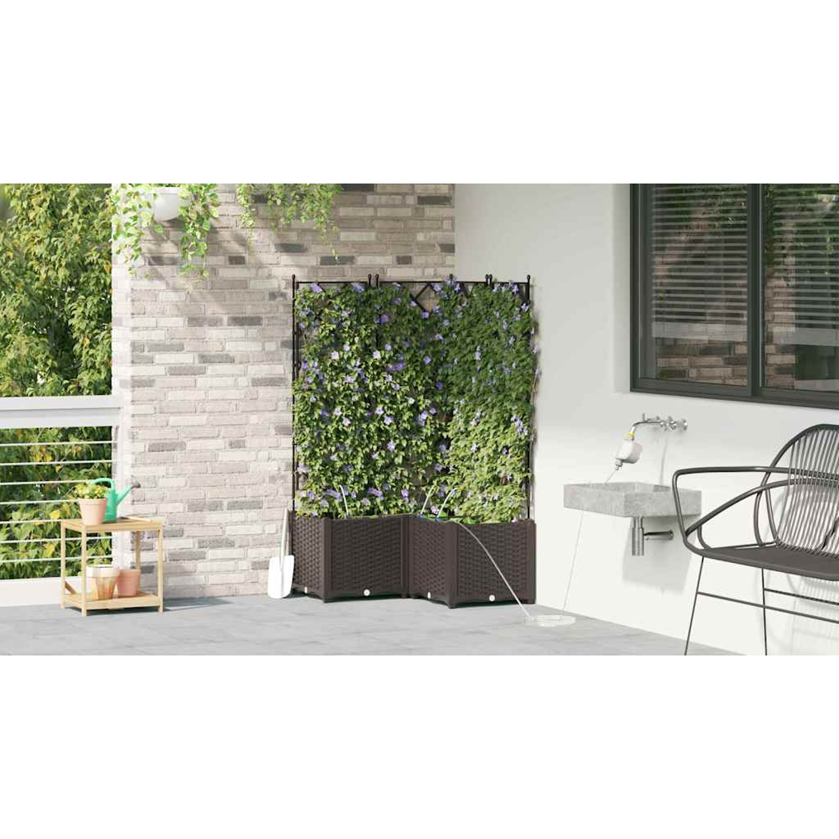 Eine Terrassenszene mit einem mit Pflanzen gefüllten Spalier, einer Backsteinmauer und einem kleinen Tisch mit Pflanzen. Ein Waschbecken und ein Stuhl sind ebenfalls zu sehen.