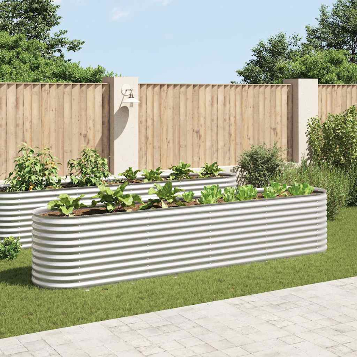 Zwei erhöhte Metall-Gartenbeete mit Gemüse. Dahinter ein Holzzaun und grünes Gras. Der Himmel ist blau.