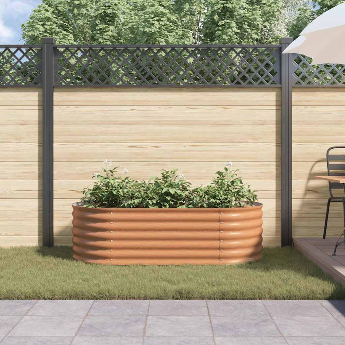 Ein Beet mit Pflanzen steht auf Gras. Dahinter ein Holzzaun mit Gitteraufsatz. Terrasse und Bäume im Hintergrund.