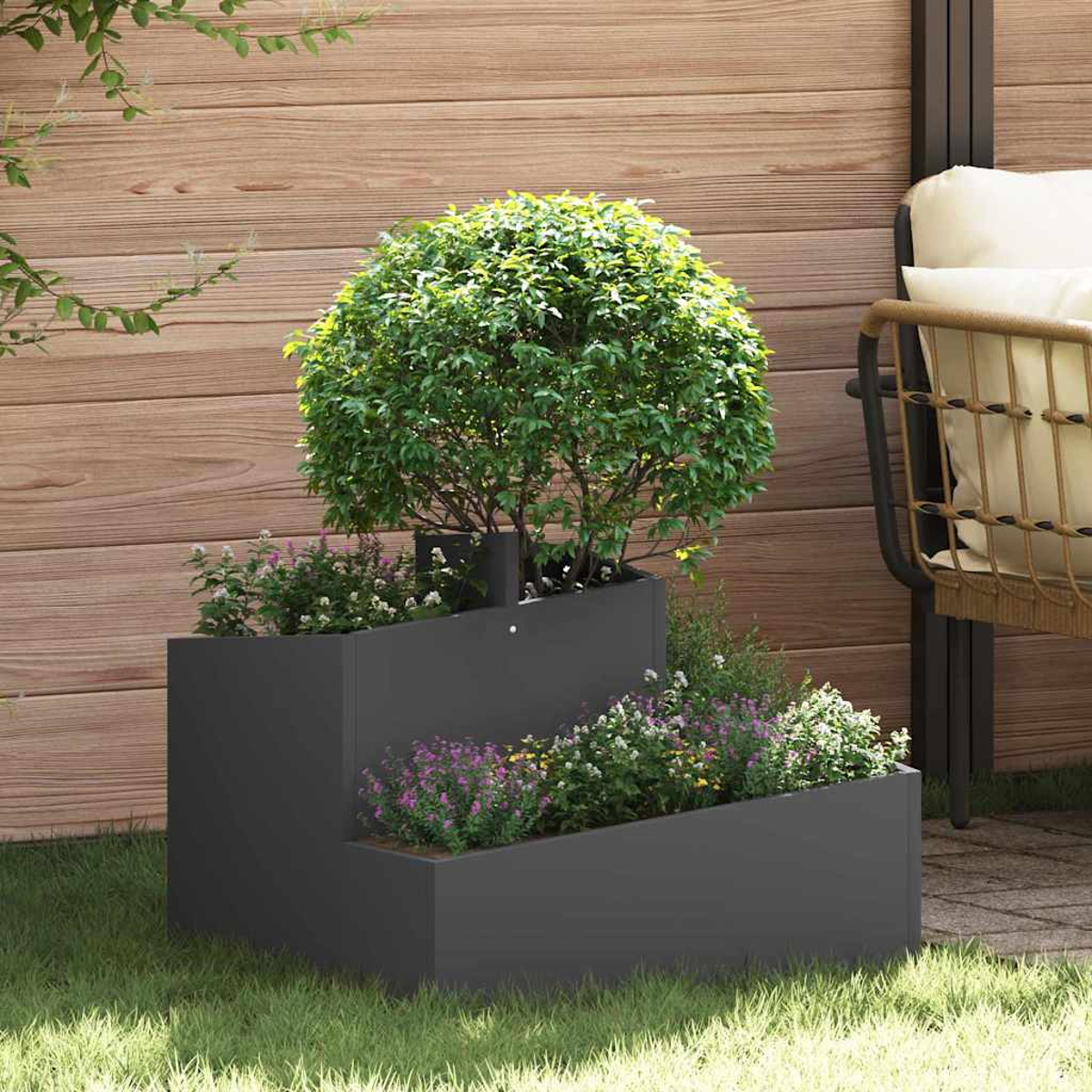 Una fioriera a più livelli con un cespuglio verde e fiori. Una recinzione in legno e una sedia sullo sfondo.