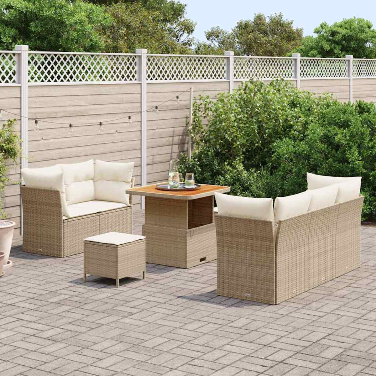 Garten-Sitzgruppe auf einer Terrasse. Sie umfasst ein Sofa, zwei Stühle, einen kleinen Tisch und einen Hocker mit cremefarbenen Kissen.