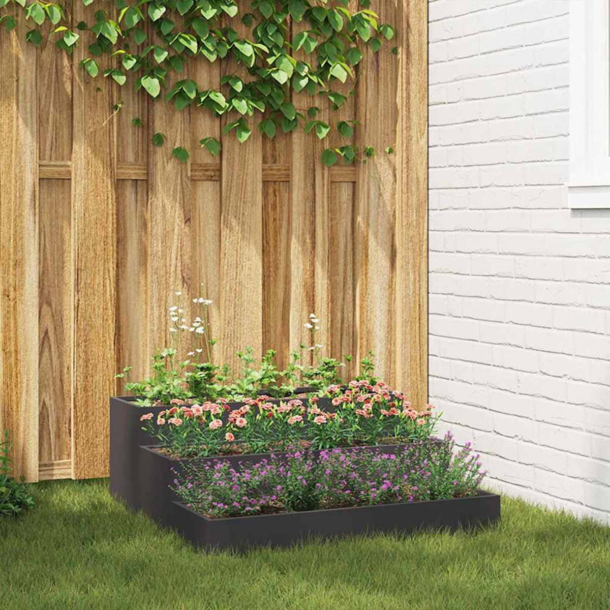 Una fioriera a più livelli con fiori rosa e viola si trova sull'erba. Una recinzione di legno e un muro di mattoni bianchi fanno da sfondo.
