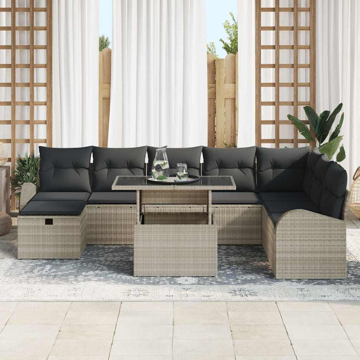 Outdoor-Ecksofa mit dunklen Kissen, Glastisch und Teppich. Weiße Vorhänge und Holzzaun im Hintergrund.