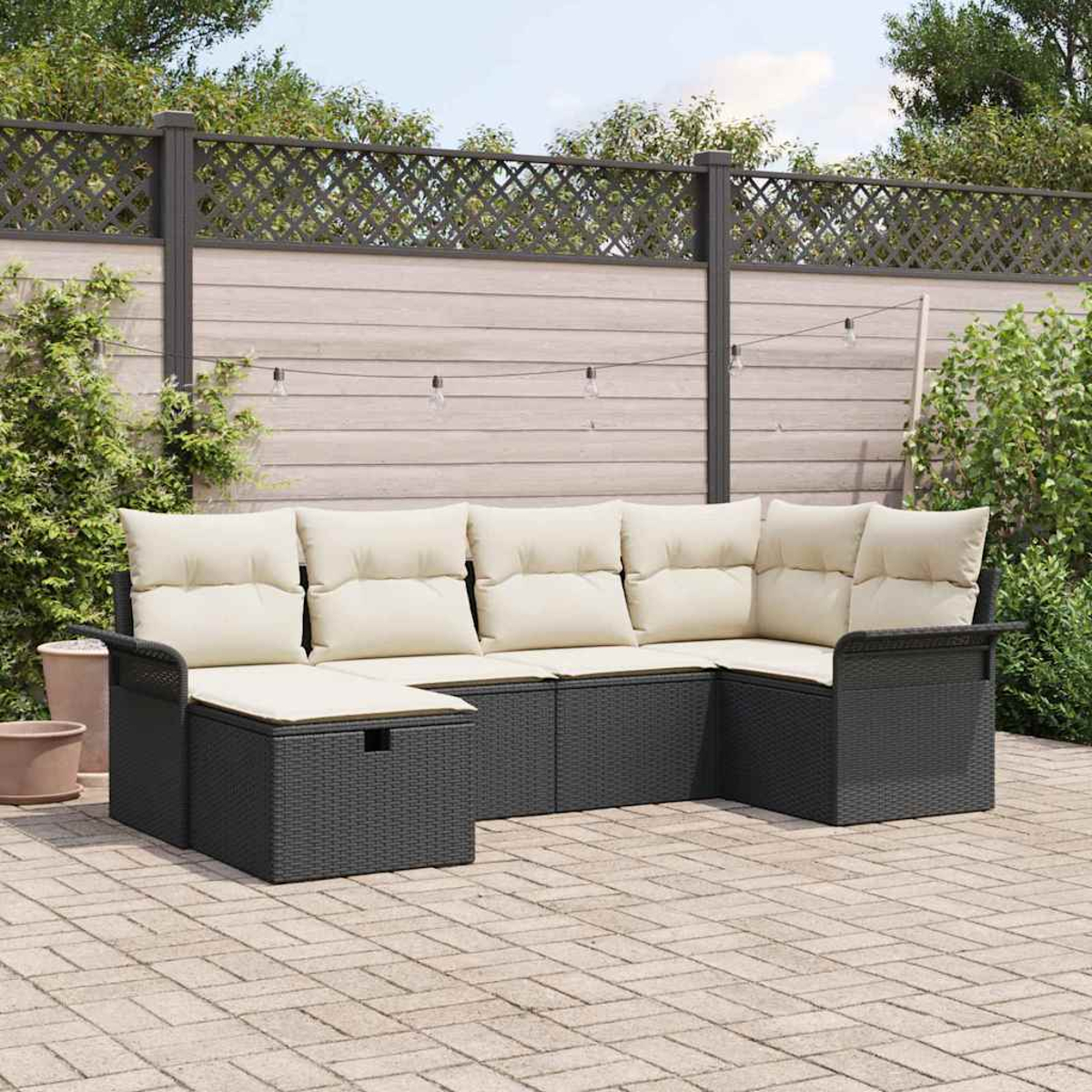 Outdoor-Ecksofa mit cremefarbenen Kissen auf einer Ziegelterrasse. Im Hintergrund befinden sich ein Zaun und Grün. Lichterketten sind gespannt.