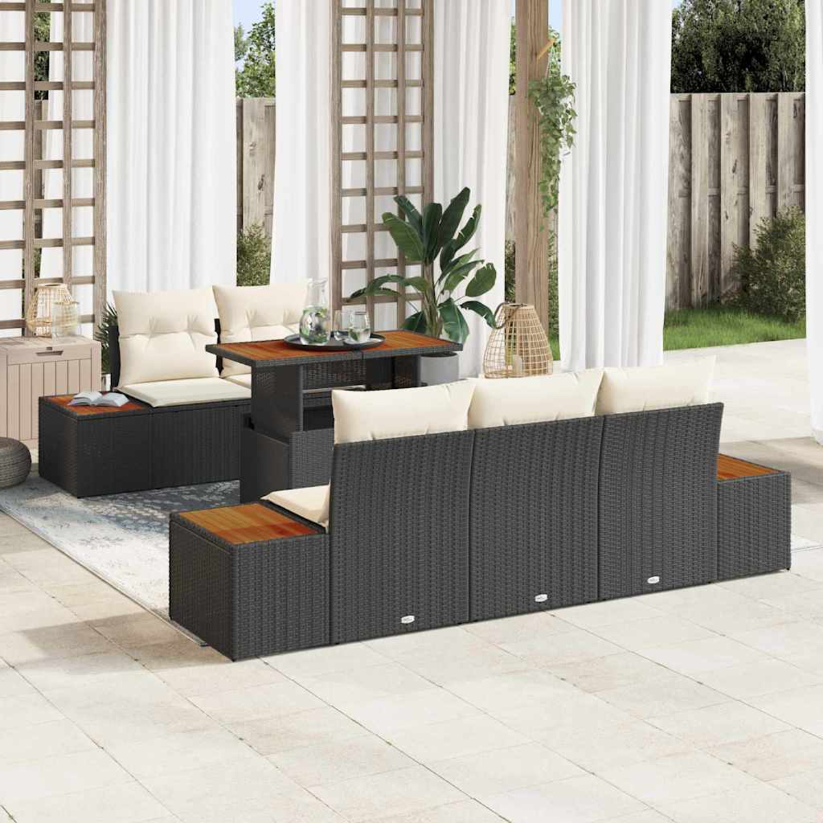 Outdoor-Wicker-Möbelset. Enthält Sofa, zwei Ottomane und Tisch. Helle Kissen, dunkles Korbgeflecht. Weiße Vorhänge im Hintergrund.