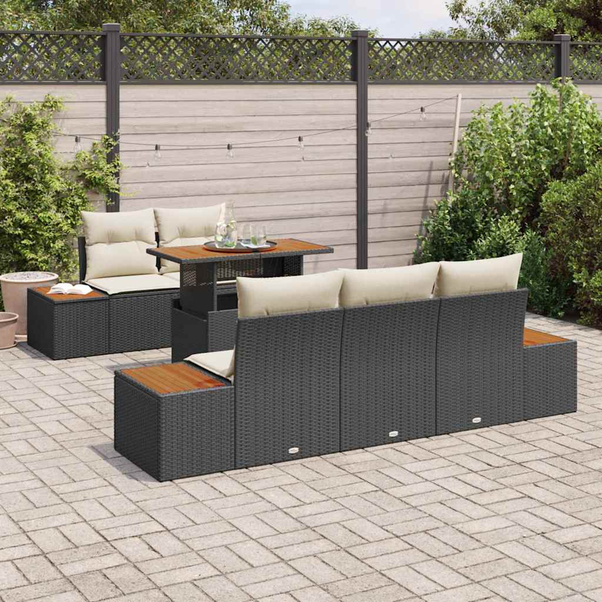 Garten-Terrassenmöbel-Set mit grauen Korbmöbeln, hellen Kissen und einem Holztisch. Die Szene umfasst einen Zaun und Grün.