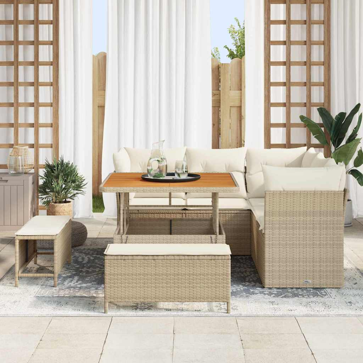 Garten-Sitzgruppe mit Tisch, Bänken und Kissen. Weiße Vorhänge, Pflanzen und Holzgitter im Hintergrund. Eine sonnige Terrasse.