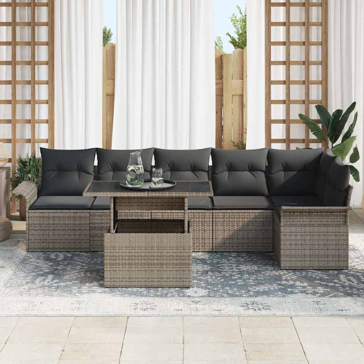 Outdoor-Sitzbereich mit grauen Kissen, einem Tisch mit Hubplatte und weißen Vorhängen. Auf dem Boden liegt ein Teppich.