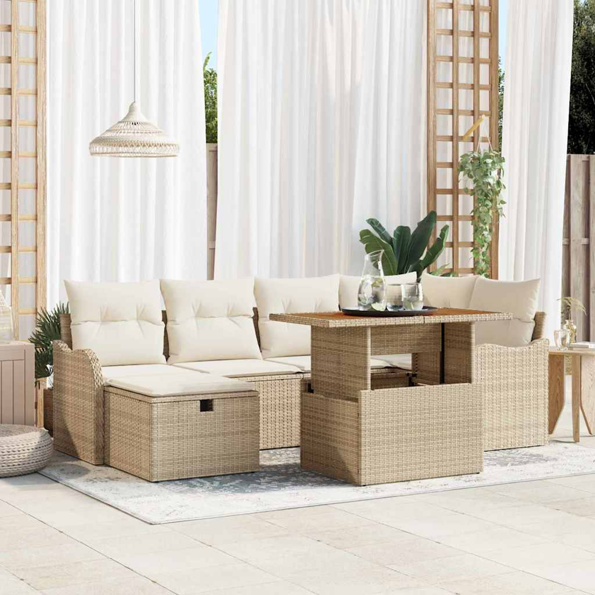 Zona de estar al aire libre con muebles de mimbre beige, cojines blancos, una mesa y cortinas blancas en el fondo.