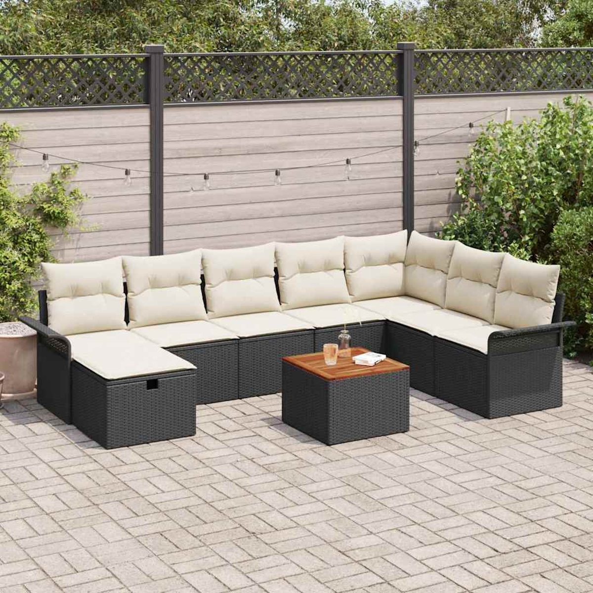 Outdoor-Ecksofa mit beigen Kissen und einem Holztisch auf einer Backstein-Terrasse, vor einem Zaun und Grün.