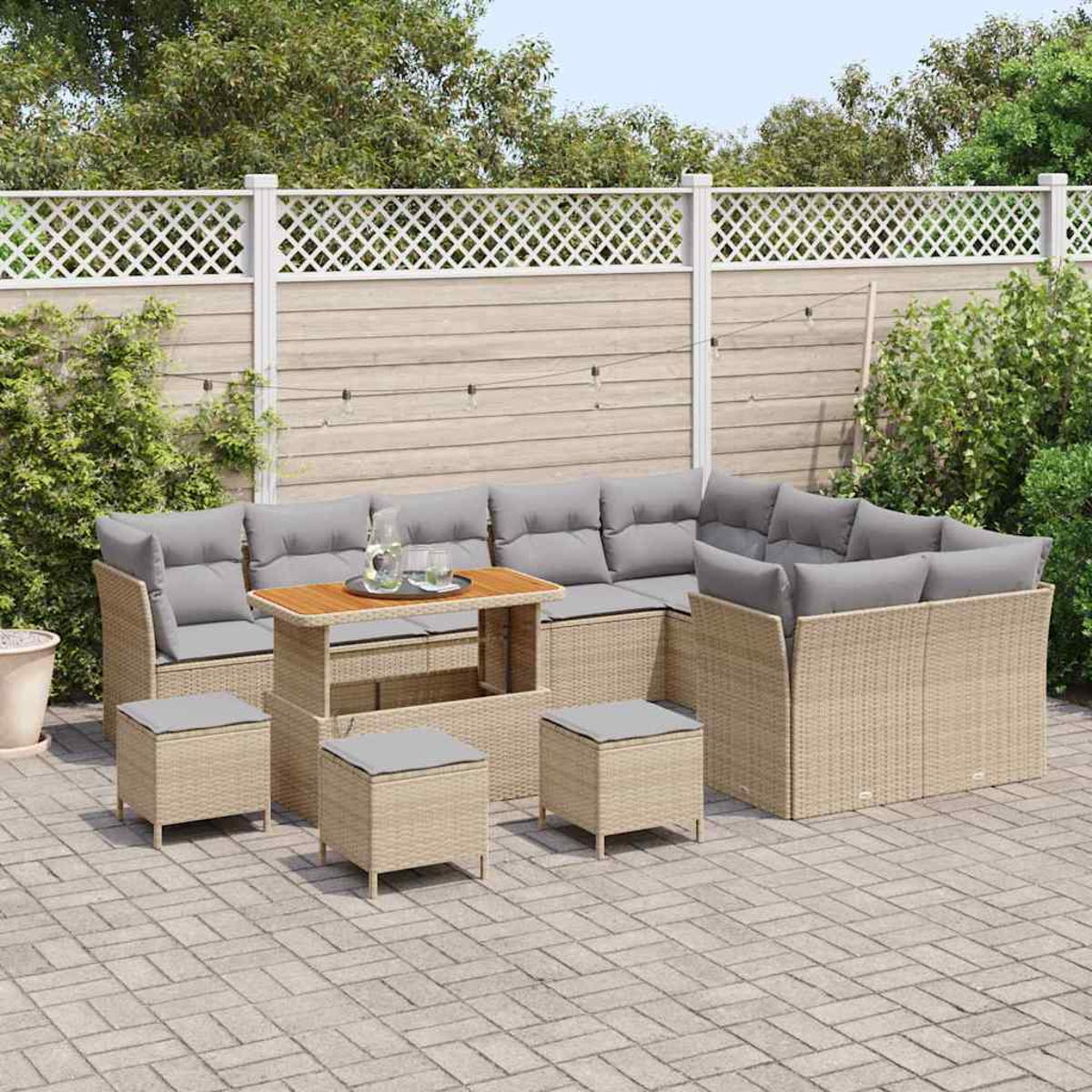 Garten-Sitzgruppe mit grauen Kissen, Tisch und Hockern auf einer Terrasse. Holzzaun mit grünem Laub im Hintergrund.