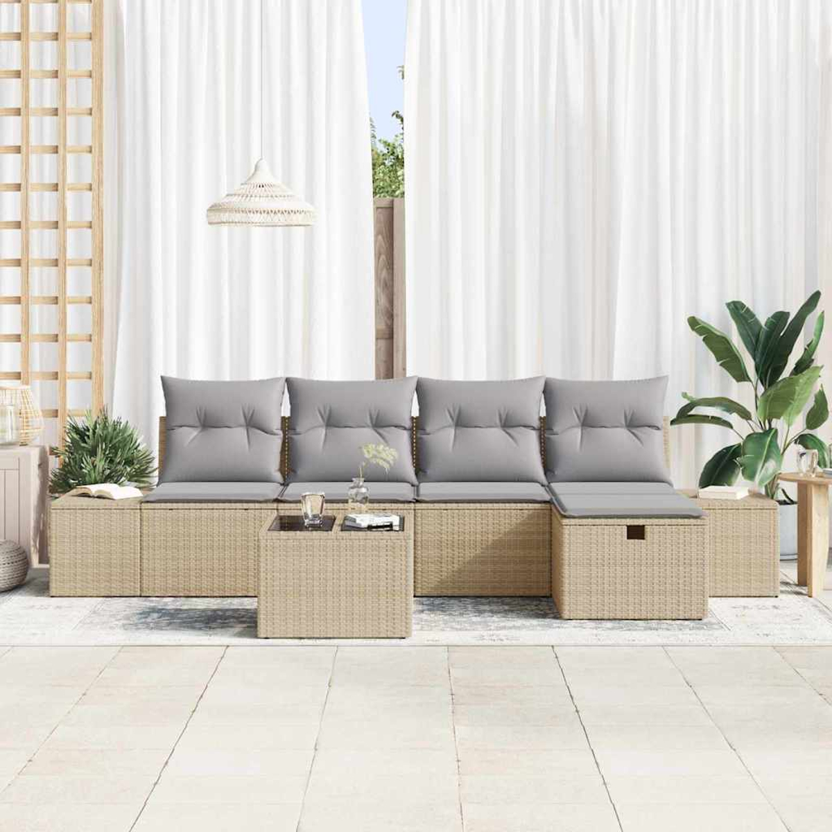 Garten-Sitzgruppe mit grauen Kissen, einem kleinen Tisch und weißen Vorhängen. Rechts ist eine Pflanze. Beige Korbmöbel.