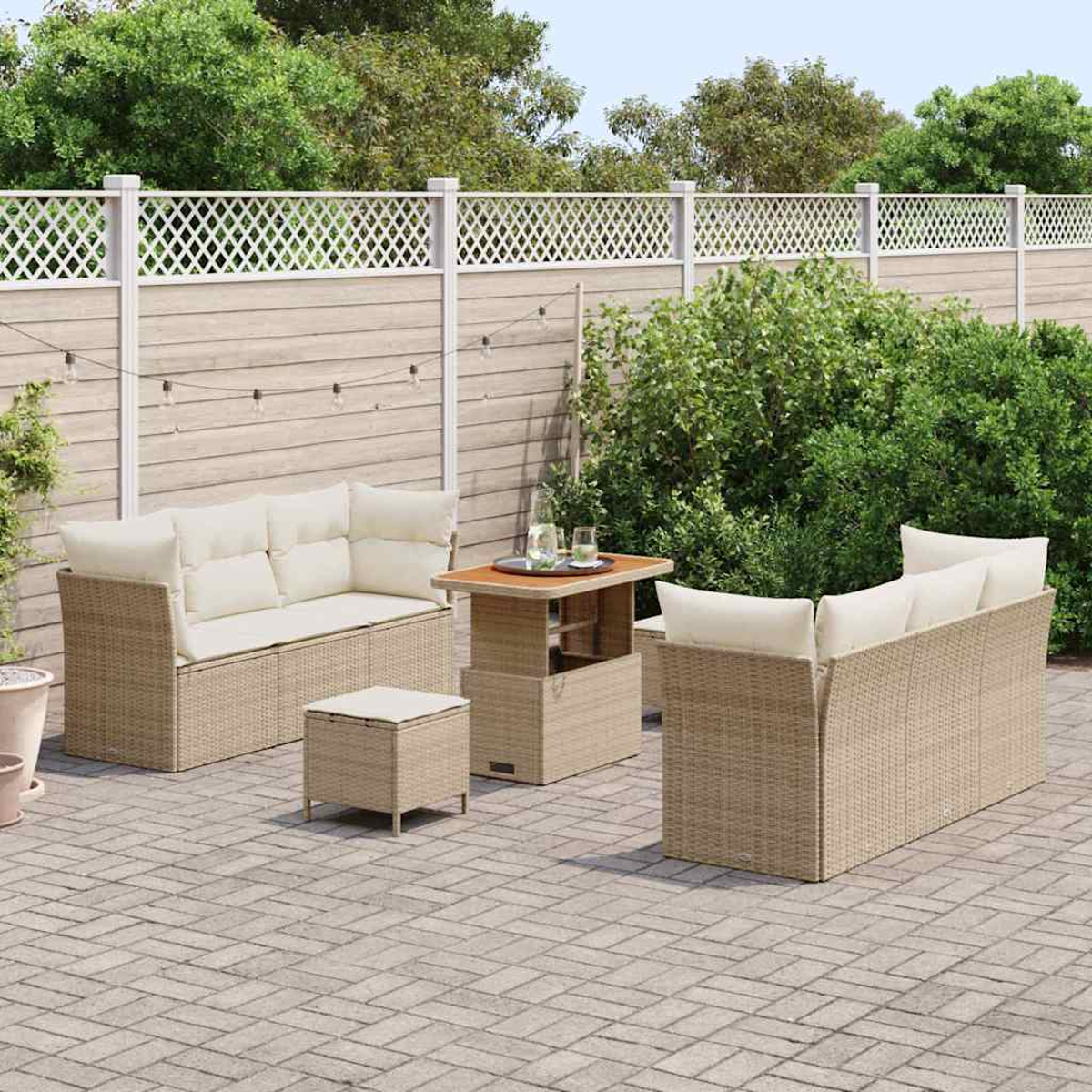 Gartenmöbel-Set aus Korbgeflecht mit cremefarbenen Kissen auf einer Ziegelterrasse. Enthält Sofa, zwei Stühle, Tisch und Hocker.