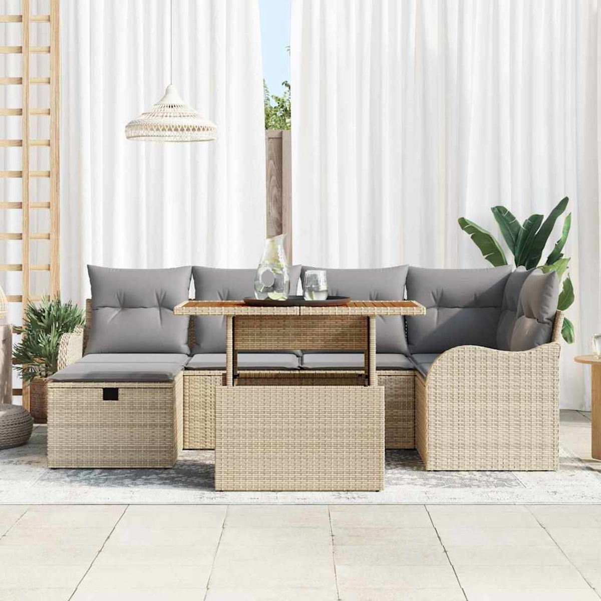 Gartenmöbel-Set aus Korbgeflecht mit grauen Kissen und Holztisch. Weiße Vorhänge und Pflanzen im Hintergrund schaffen Ambiente.