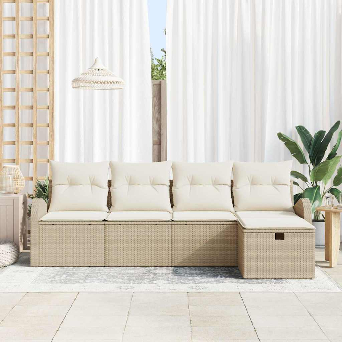 Sofá de mimbre para exteriores con cojines crema. Cortinas blancas y una planta grande al fondo. Se ve una lámpara colgante.