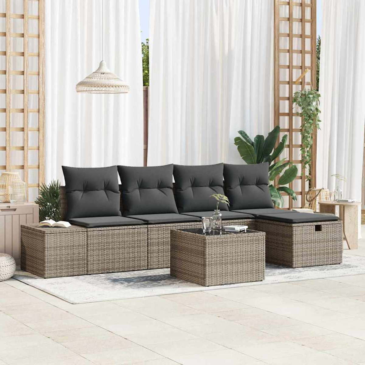Garten-Sitzgruppe mit grauen Kissen. Beinhaltet ein Sofa, eine Ottomane und einen Couchtisch auf einem Teppich, mit weißen Vorhängen im Hintergrund.