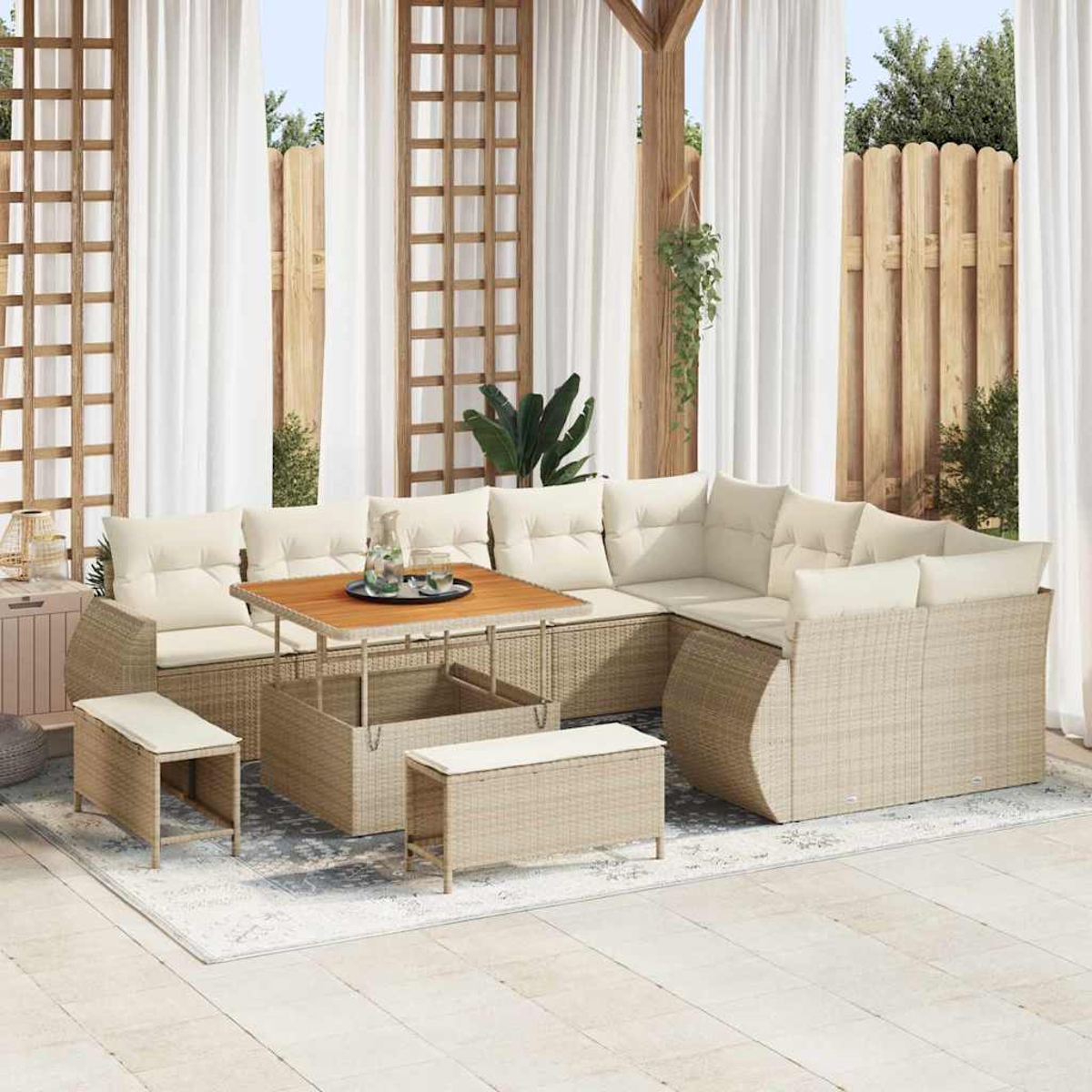 Beiges Outdoor-Korbsessel mit Kissen, Holztisch, Bänken und weißen Vorhängen. Auf einem Teppich und einer Terrasse.