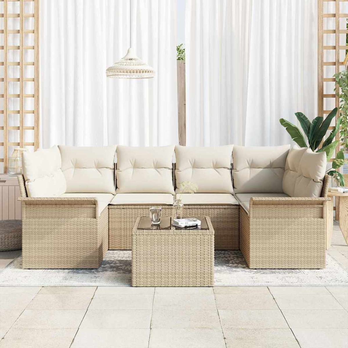 Garten-Sitzgruppe. Beiges Korban-Sofa mit cremefarbenen Kissen, Couchtisch und weißen Vorhängen im Hintergrund. Eine Pflanze steht an der Seite.