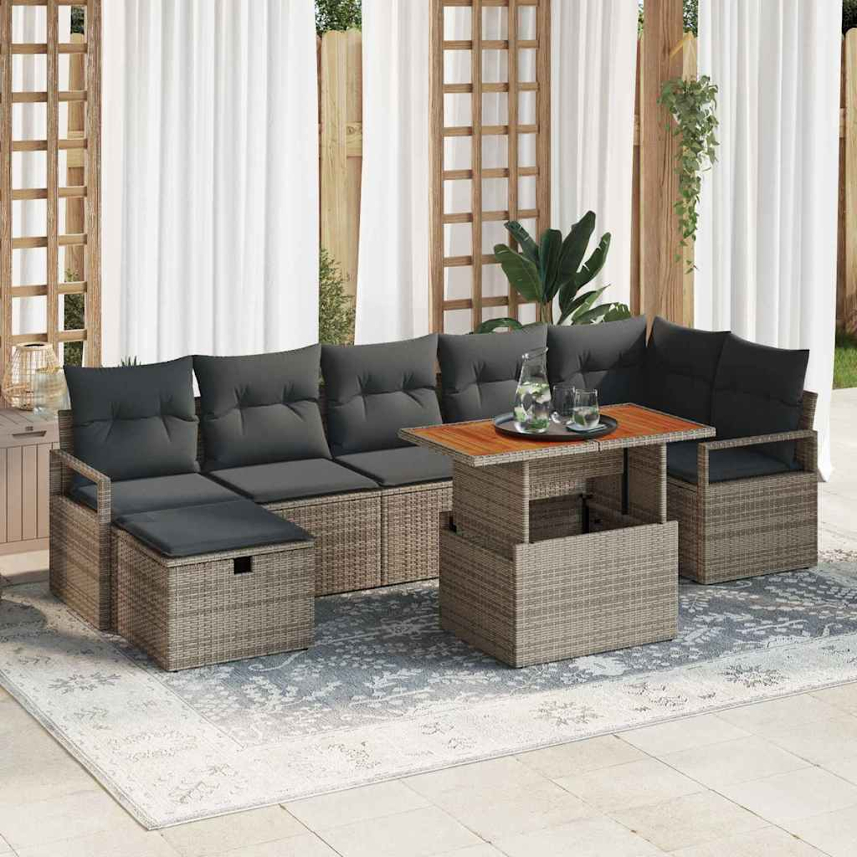 Terrassenset im Freien mit grauen Kissen, einem Couchtisch und einem Teppich. Weiße Vorhänge und Holzgitter im Hintergrund.