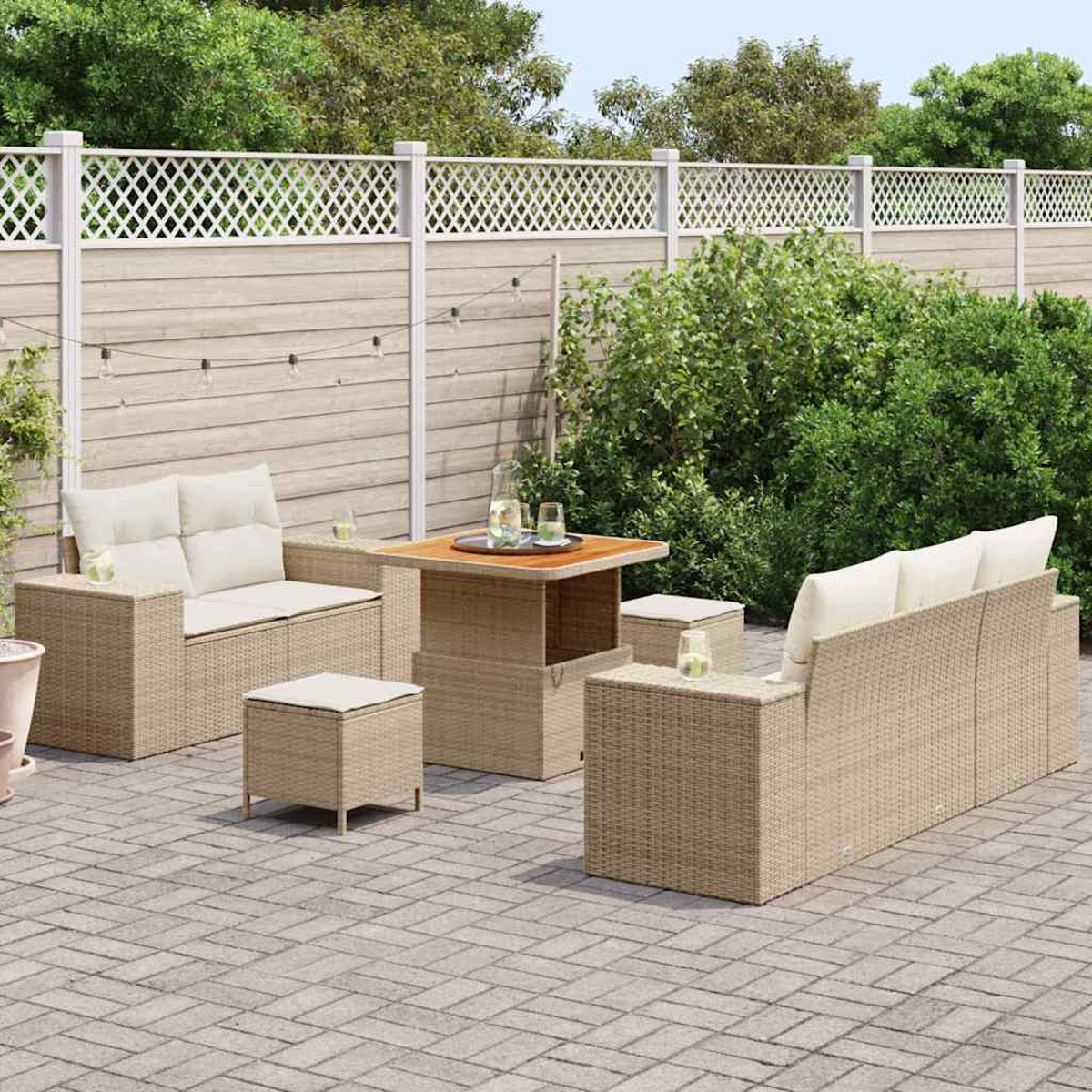 Garten-Sitzgruppe auf der Terrasse: zwei Sofas, zwei Ottomane und ein Tisch. Hintergrund: Zaun und Grün.