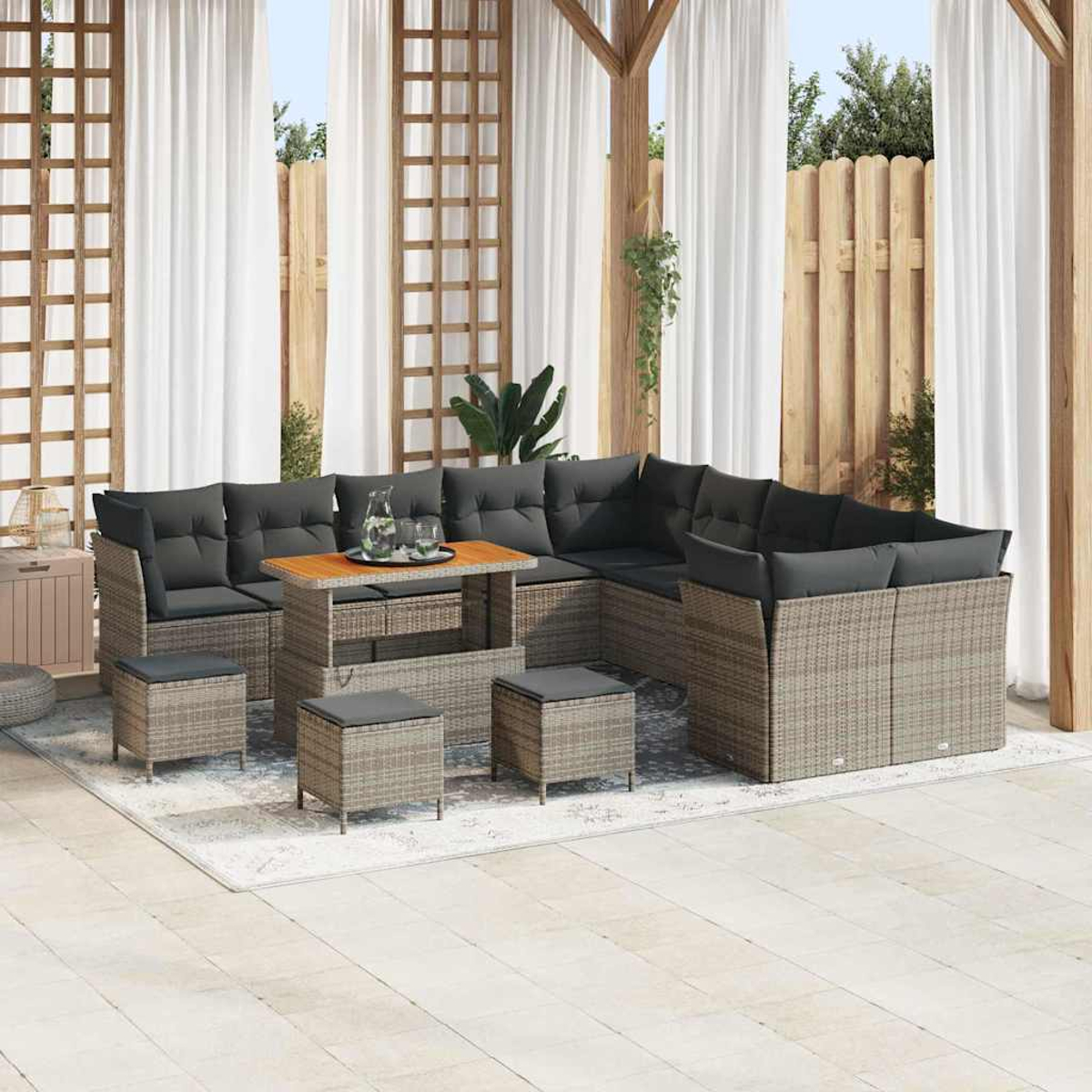 Terrassenset mit grauen Kissen. Enthält ein großes Ecksofa, einen Tisch und Hocker, alles auf einem gemusterten Teppich angeordnet.
