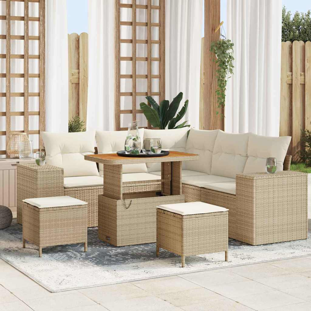 Set per patio all'aperto. Mobili in vimini con cuscini beige e un tavolo in legno. Tende bianche e una staccionata in legno sullo sfondo.
