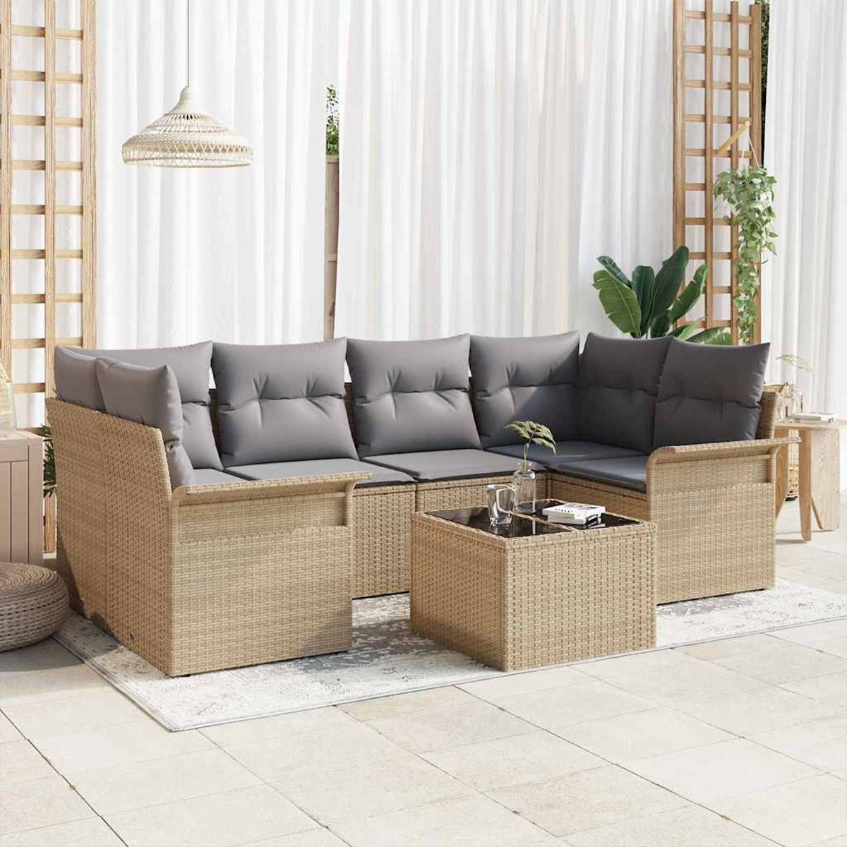 Geflochtenes Outdoor-Ecksofa mit grauen Kissen, Couchtisch mit Glasplatte, weißen Vorhängen und Hängelampe.