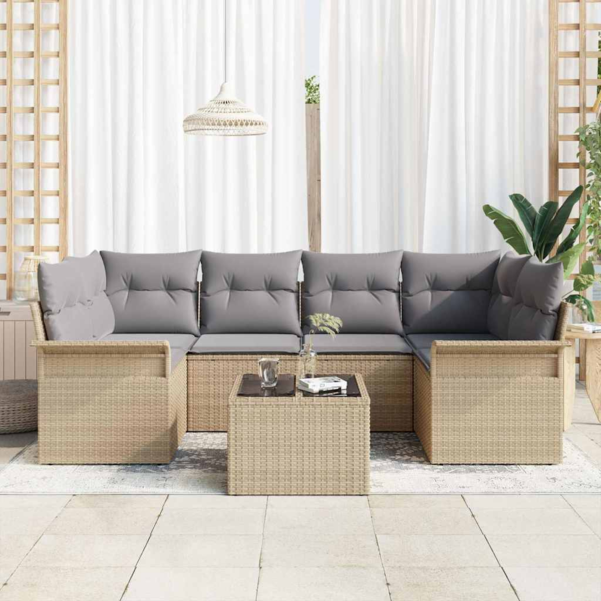 Rattan-Sofa-Set im Freien mit grauen Kissen, einem Couchtisch und weißen Vorhängen im Hintergrund, in der Nähe einer Pflanze.