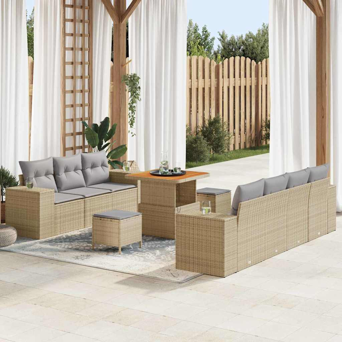 Garten-Terrassenset mit gewebten beigefarbenen Sofas und grauen Kissen, einem Holztisch und weißen Vorhängen. Im Hintergrund ist ein Holzzaun zu sehen.