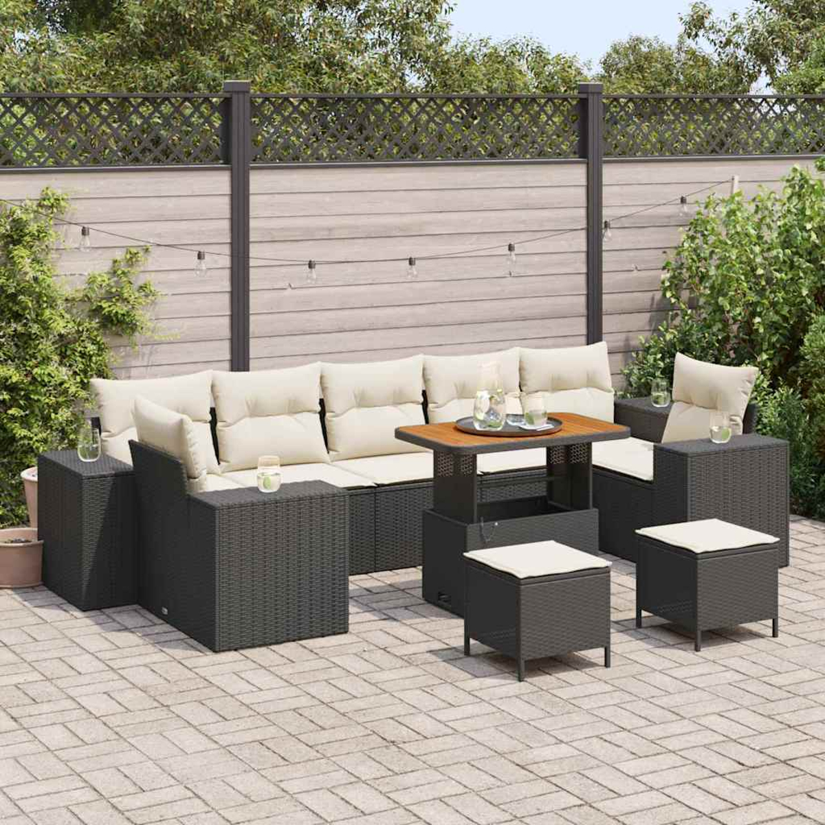 Conjunto de muebles de mimbre para exteriores con cojines beige y una mesa de madera, colocados en un patio. Una valla y vegetación al fondo.