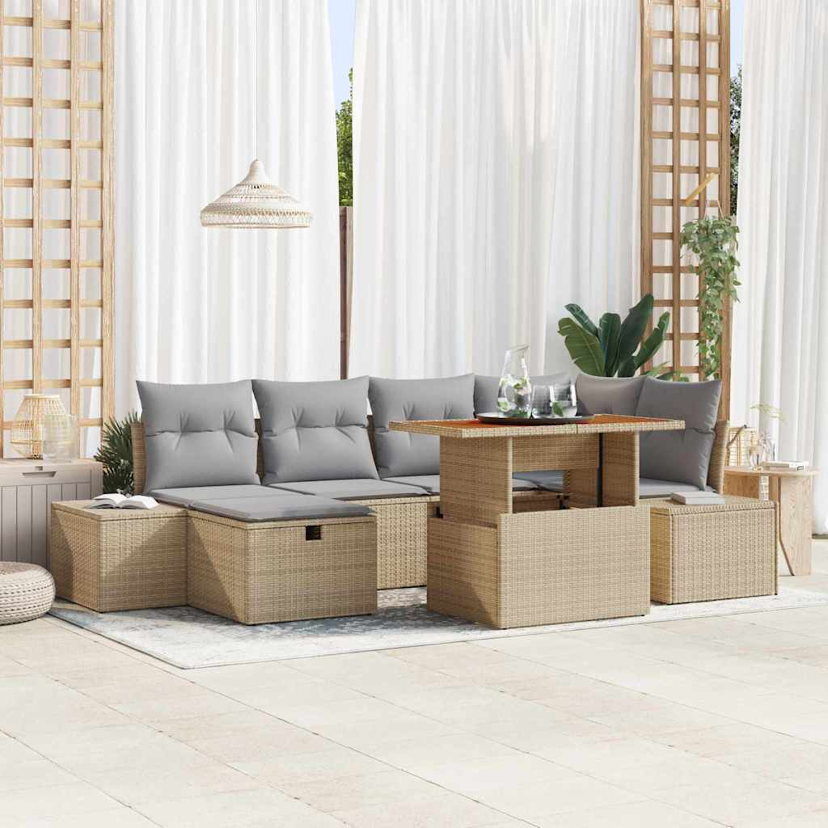 Außenbereich mit beigen Korbmöbeln, grauen Kissen und einem Tisch mit Hubfunktion. Weiße Vorhänge und ein Spalier im Hintergrund.