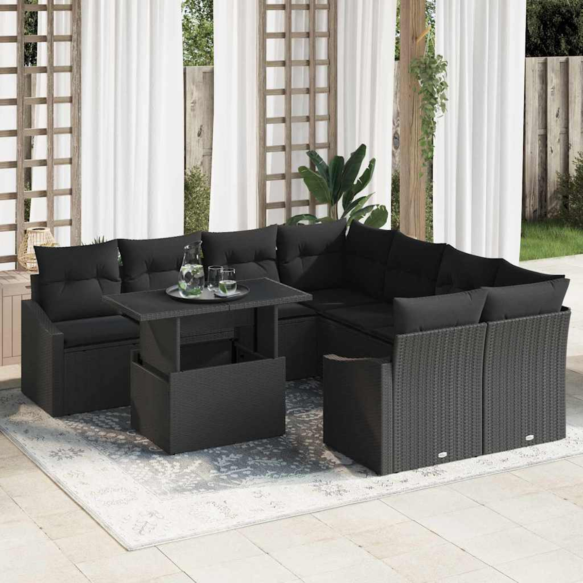 Schwarzes Ecksofa mit Kissen und einem Tisch mit Getränken im Freien. Auf einem gemusterten Teppich mit weißen Vorhängen und Holzstrukturen.