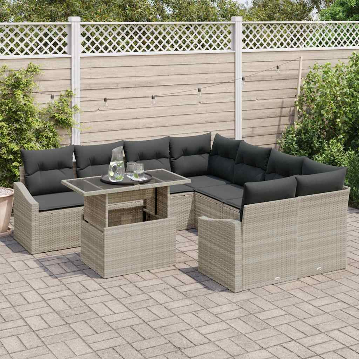 Garten-Terrassenset mit grauen Kissen. Tisch mit Getränken. Beige Korbmöbel. Zaun im Hintergrund.