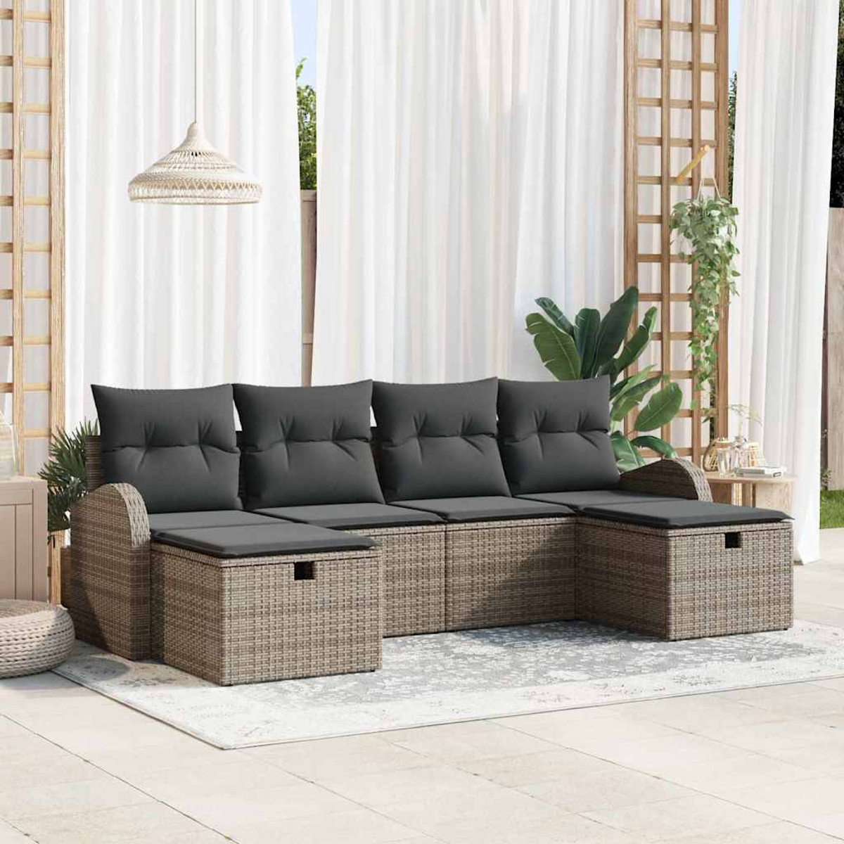 Sofá seccional exterior con cojines grises. Base estilo mimbre. Cortinas blancas y enrejado de madera al fondo. Alfombra en el suelo.