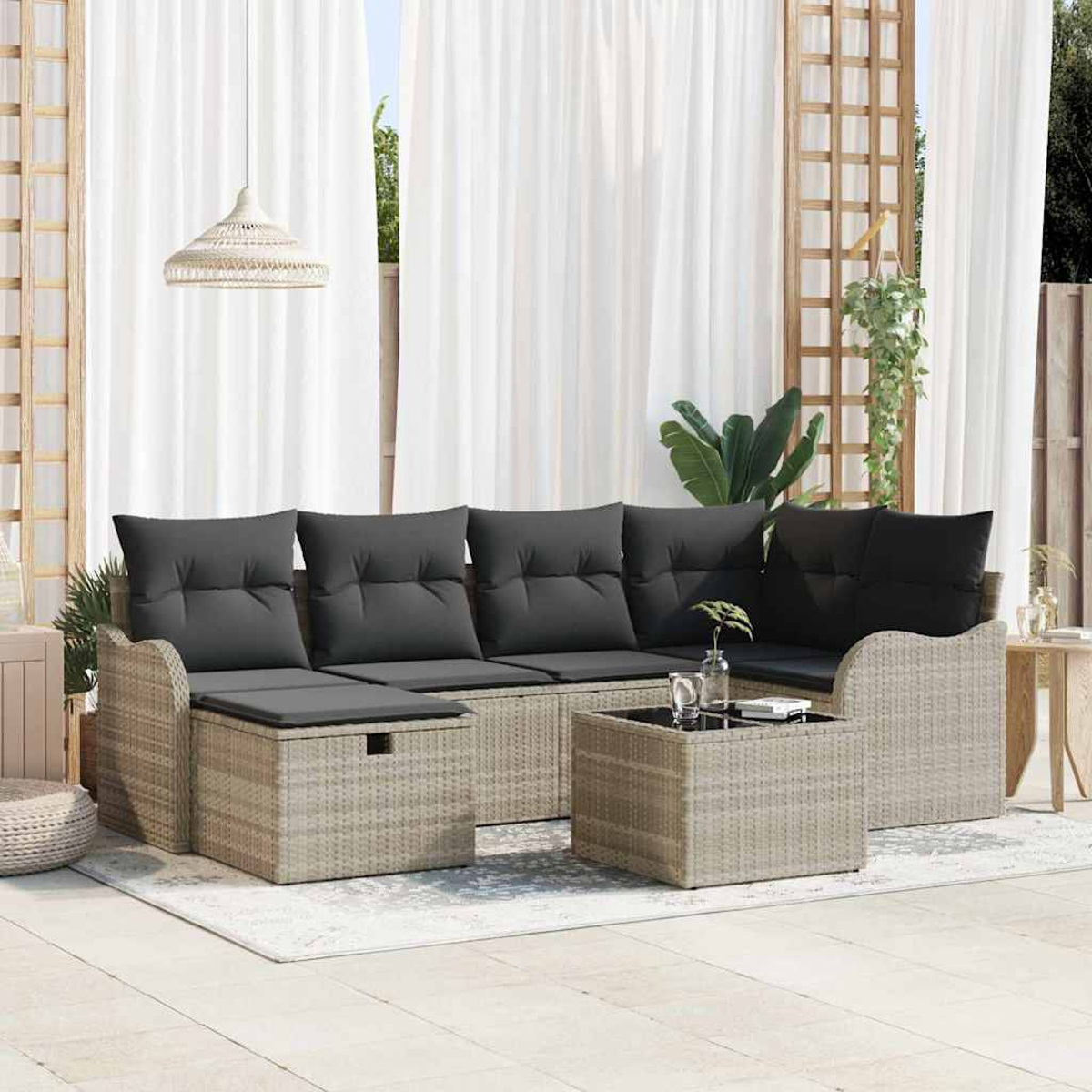 Terrassengarnitur mit hellbraunen Korbmöbeln, grauen Kissen, einem quadratischen Couchtisch und weißen Vorhängen im Hintergrund.