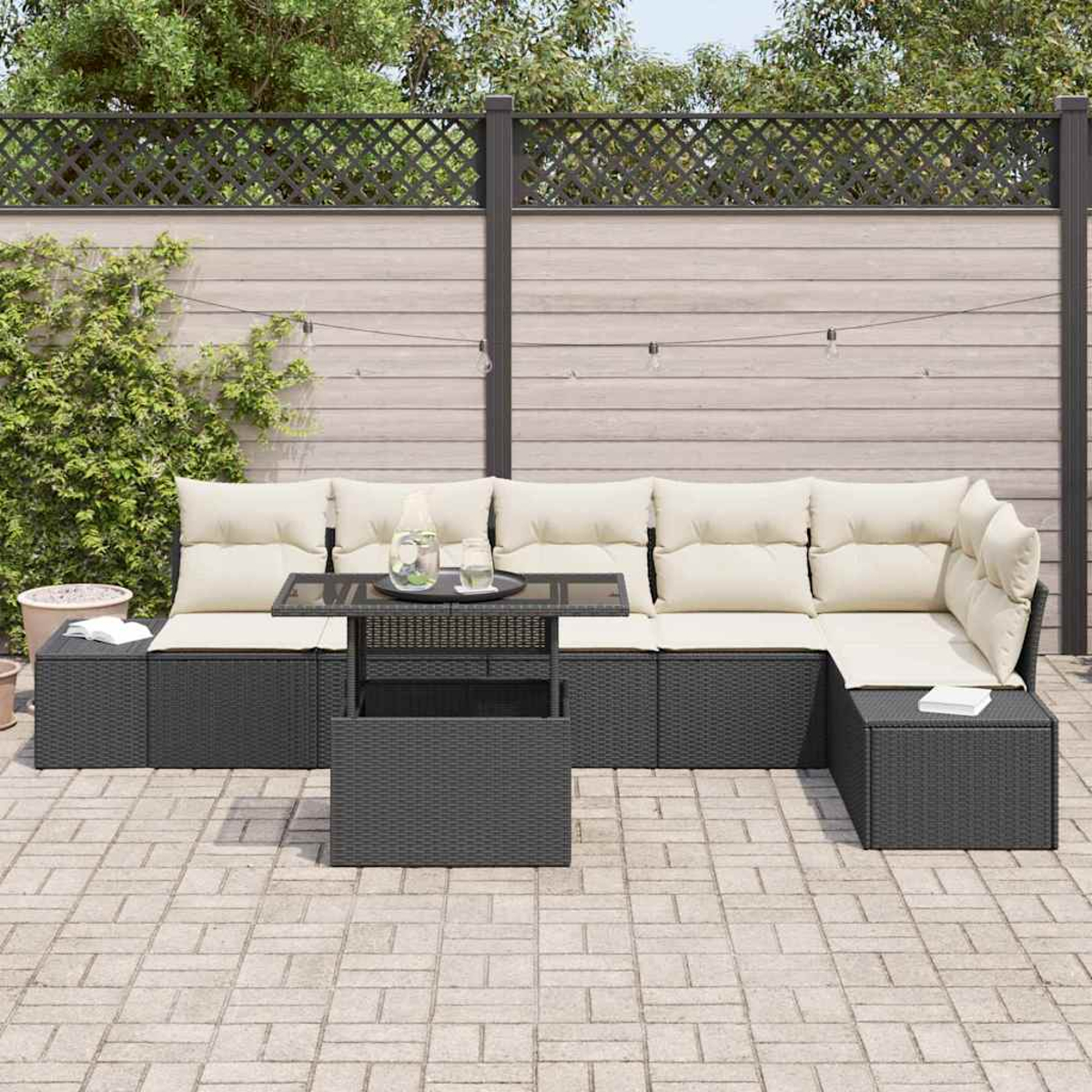 Outdoor-Ecksofa mit cremefarbenen Kissen und einem Tisch mit Glasplatte. Im Hintergrund ein Holzzaun und Grün.